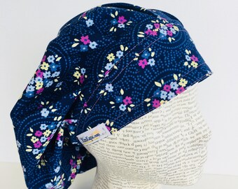 Traditional Bouffant Scrub Cap scrub hat featuring a dark blue material with flowers in pink blue white and yellow