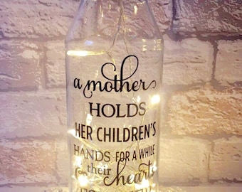 Message on a bottle with quote 'A mother holds her children's hands for a while & their hearts forever'.