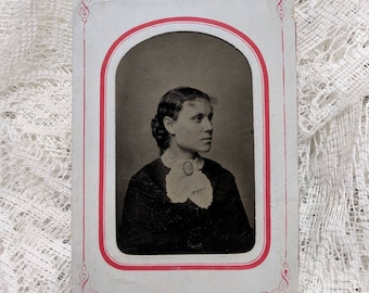 Tintype photograph of a beautiful fashionably dressed woman in a paper frame wearing a cameo brooch
