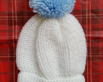 Child,s white pom-pom hat with light blue pom-pom