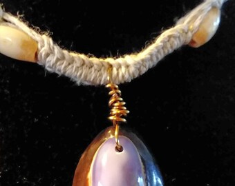 Purple Cowry pendant with three bone beads on each side on a hemp chain