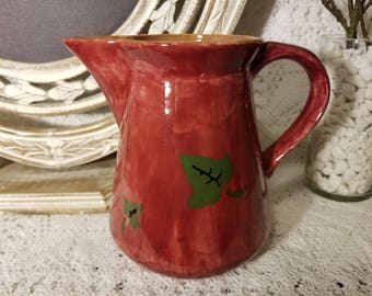 Maroon pitcher with green leaves