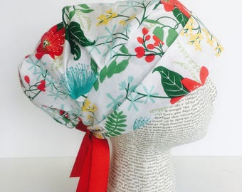 Ribbon Tie Back Surgical Scrub Cap scrub hat featuring a white material with flowers in red yellow blue and green with a matching red ribbon