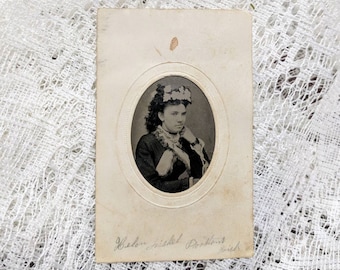 Identified Tintype photograph of a beautiful fashionably dressed woman in a paper frame wearing a smirk