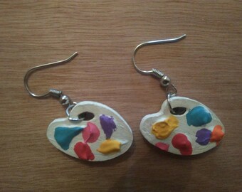 Earrings dangle in the shape of painter's palette