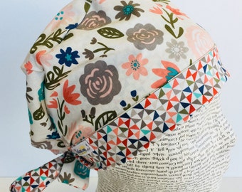 Tie Back Scrub Cap scrub hat featuring a beige material with flowers in peach teal and green with a coordinating band 2t