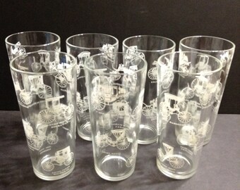 Group of 7 mid-century glass tumblers, clear glass with white horseless carriages pattern, 6 1/2 inches tall.