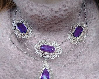 Fabulous filigree statement festoon with detailed lace-like silver settings holding gorgeous faceted amethys colored pastes. Great necklace!