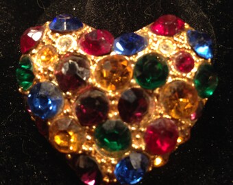 Gold heart shaped brooch with many different brightly colored rhinestones