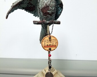 Heartsongs - There is a Fountain is an altered wood poker chip with paper hymn snippets, metal findings and charms