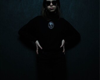 Black turtleneck, embroidered white cameo.