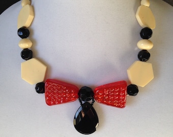 A bow shaped necklace, in orange, black and off white.