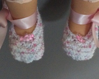 Pretty in pink. Newborn baby booties with pink satin ribbon and pink beads.