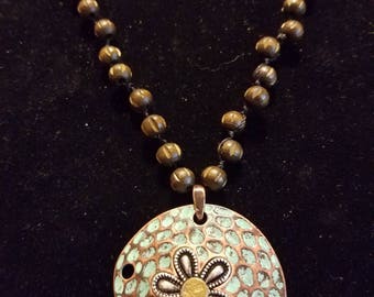 Copper sand dollar with .22 Remington casing in the center long wooden bead chain each one tied separate.