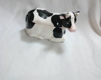 Vintage cow sugar bowl. No spoon is with it. Black and white. Cow is lying down. Ceramic