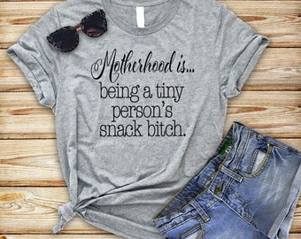 Graphic tee, funny t-shirt, funny t shirt, funny sayings, Motherhood is...being a tiny person's snack bitch™ brand shirt.