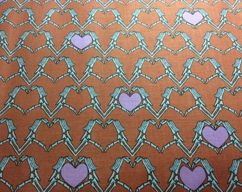 Riley Blake Zombie Love fabric. Orange background with skellington arms holding a pink heart