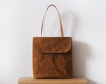 Waxed canvas tote bag with front flap and tan leather handles