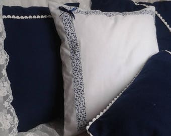 white cushion edged with a blue floral Ribbon