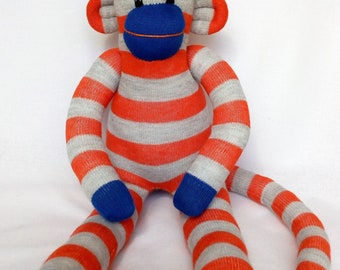 Orange and grey and blue striped Sock Monkey with blue striped pom pom hat