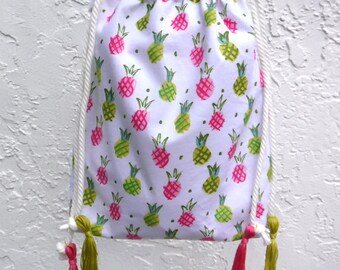 Pineapple-print crossbody bag with drawstring. Fun tropical fruit purse in white, pink, and green. Show off your summer style!