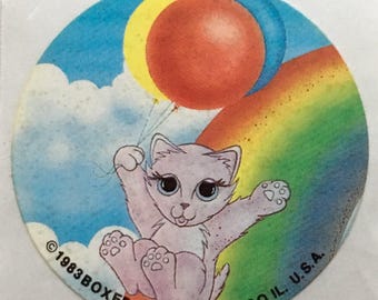 Kitty sliding down rainbow holding balloons sticker, 1983