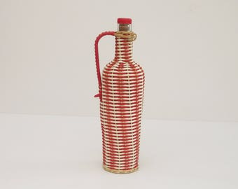 Vintage glass bottle dressed in red plastic and white Folk, 1960's