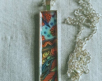 Handmade pendant containing an intricate hand coloured design.