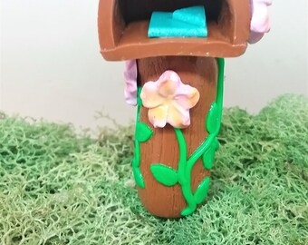 Fairy garden miniature accessories. Miniature mailbox with pale purple flowers.