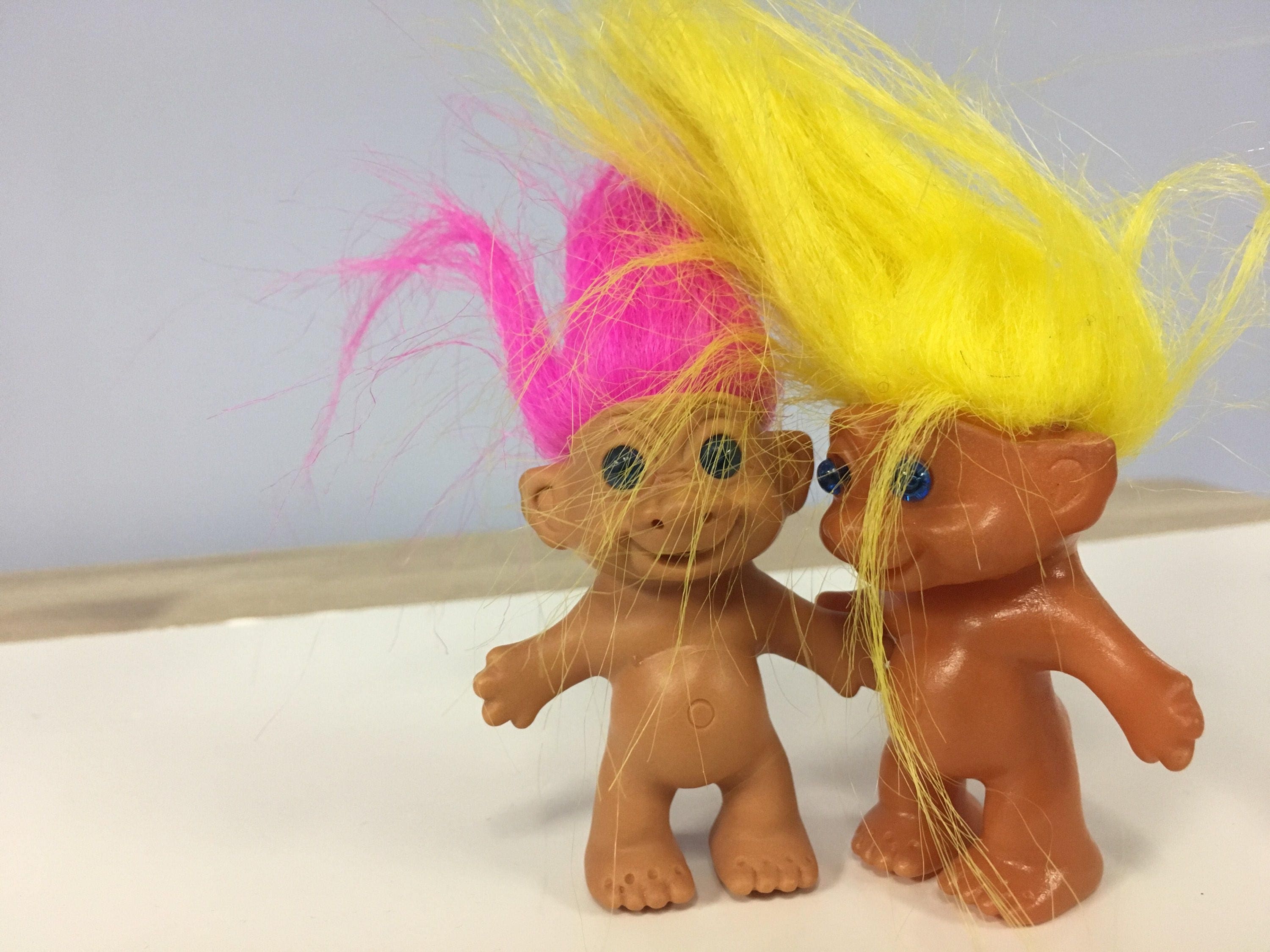 two small treasure troll dolls with pink and yellow hair