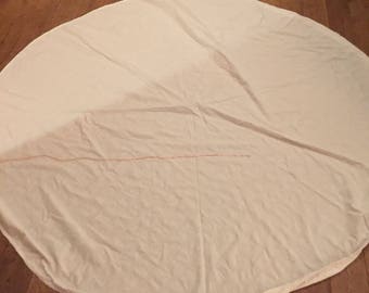 A large, vintage circular, white, textured tablecloth.