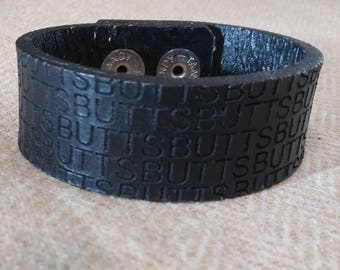 Leather cuff that says BUTTS on it