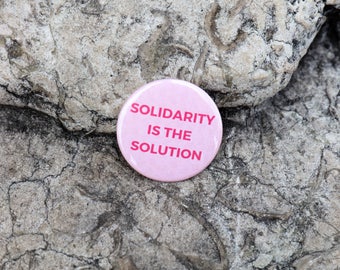 Badge à épingle rose | Pin's | Slogan Solidarity is the Solution | Imprimé à Paris| Made in France | Marque française engagée