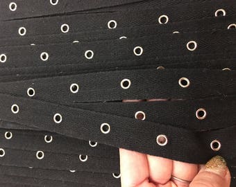 3/4" black eyelet tape, grommet tape with nickel, silver eyelets on cotton trim tape. This craft trim is sold by the yard.