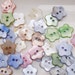 A pack of 15 flower shaped, shell buttons, 14mm. Various colours.