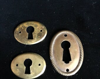 Set of three antique brass key hole covers.