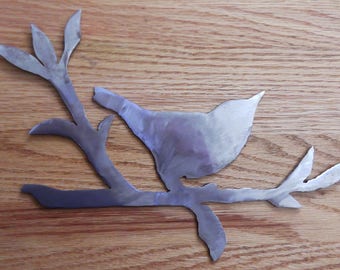 Torch cut bird on a branch from steel