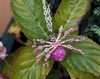 Pink and gold spider necklace made of beads.