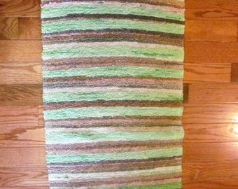 Rag rug with fringes.Woven greens and browns stripes pattern.Oblong