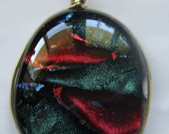 Dichronic Glass pendant. It is two by one and a quarter. It is wrapped in brass. It is red and turquoise.