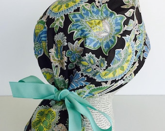 Ponytail Scrub Cap scrub hat featuring a gray material with flowers in teal yellow and white with a matching ribbon