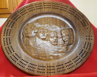 This is a beautiful Cribbage Board. It has the presidents on Mount Rushmore in the center of it.