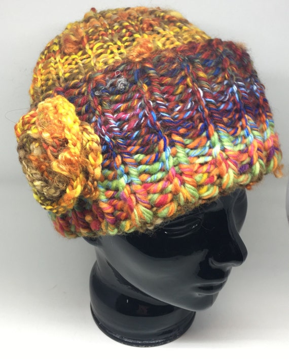 Handknit midweight winter hat made from handspun yarn of wool. Bright variegated yarn is fun to wear. Features an elegant flower detail