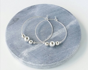 Sterling silver hoop earrings with silver beads.