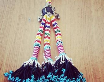 Borlon Kuchi of beads of different colors and piece of metal.