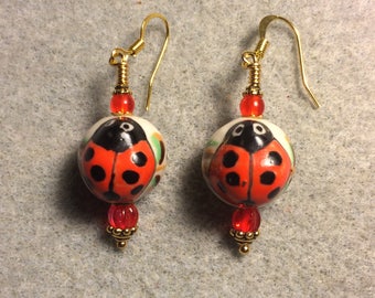 Red and black ceramic ladybug bead earrings adorned with red Czech glass beads.