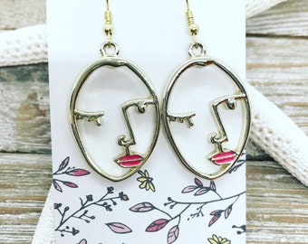 Gold tone Picasso face earrings with pink lips.
