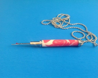 Magnetic seam ripper in the color of strawberries & cream with little black seeds and, has a satin chrome finish