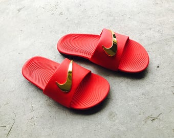 red nike slides with gold check