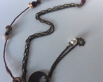 Lariat style necklace adorned with shells, gem stones, glass beads and bronze chains accent a beautiful bronze metal focal piece